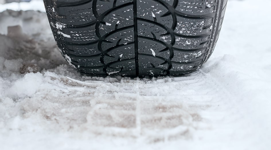 A close up of a tire making a tread in heavy snow.